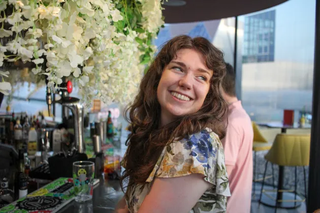 A photo of me in front of a flowery bar, I'm looking off to the right of the frame.